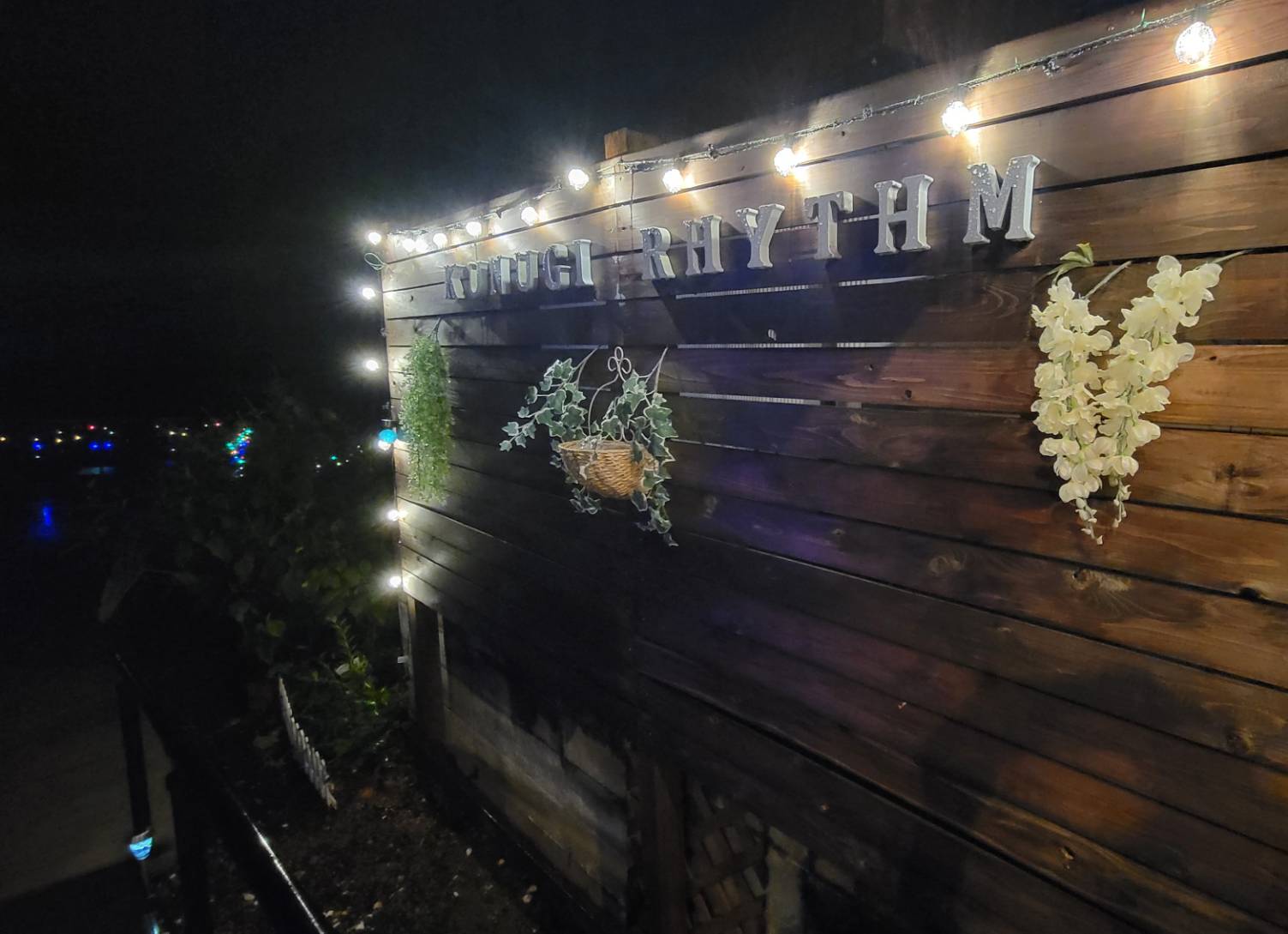 夜にライトアップされたくぬぎリズムの木製看板